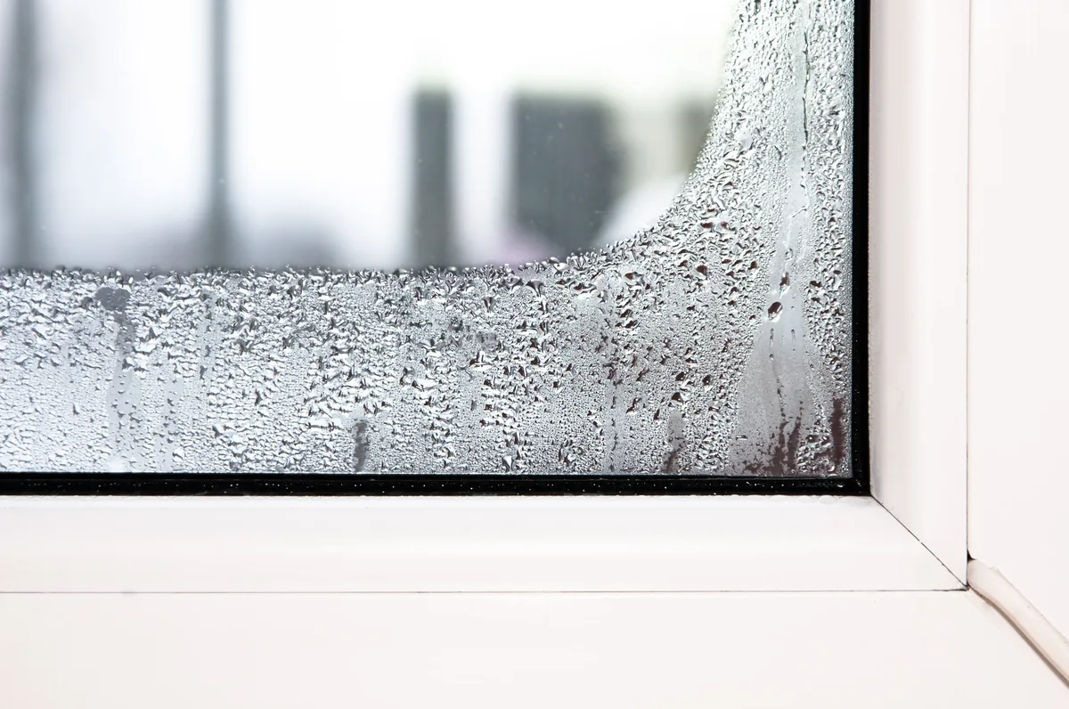 قطرات تكاثف على الحافة السفلية لزجاج مزدوج في إطار UPVC أبيض