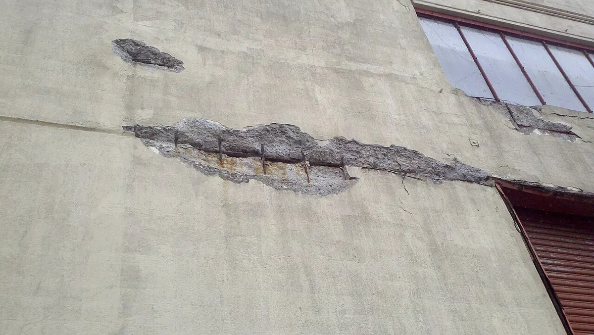 Spalled concrete exposing rusted reinforcing bar