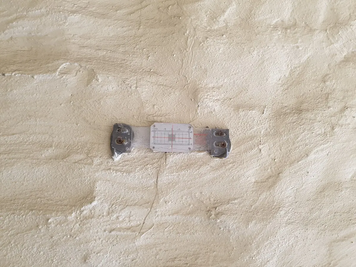 Crack monitor fixed across a fine crack in a rendered wall