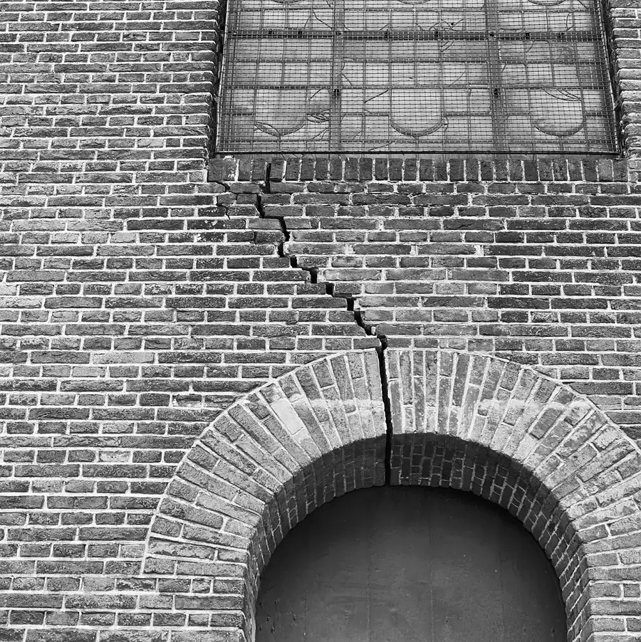 Stepped crack running from below a window down to a brick arch